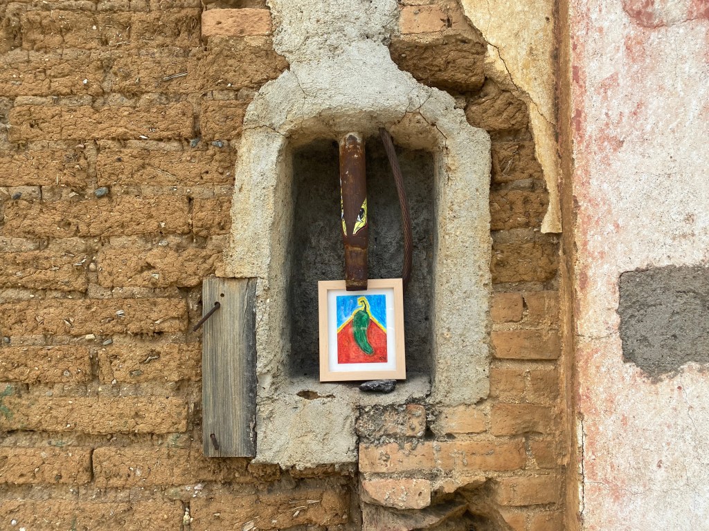 Bold pastel drawing of framed artwork of a chile serrano hung in the streets of Oaxaca City. This was left behind as a part of the experimental installation and performance of free art.